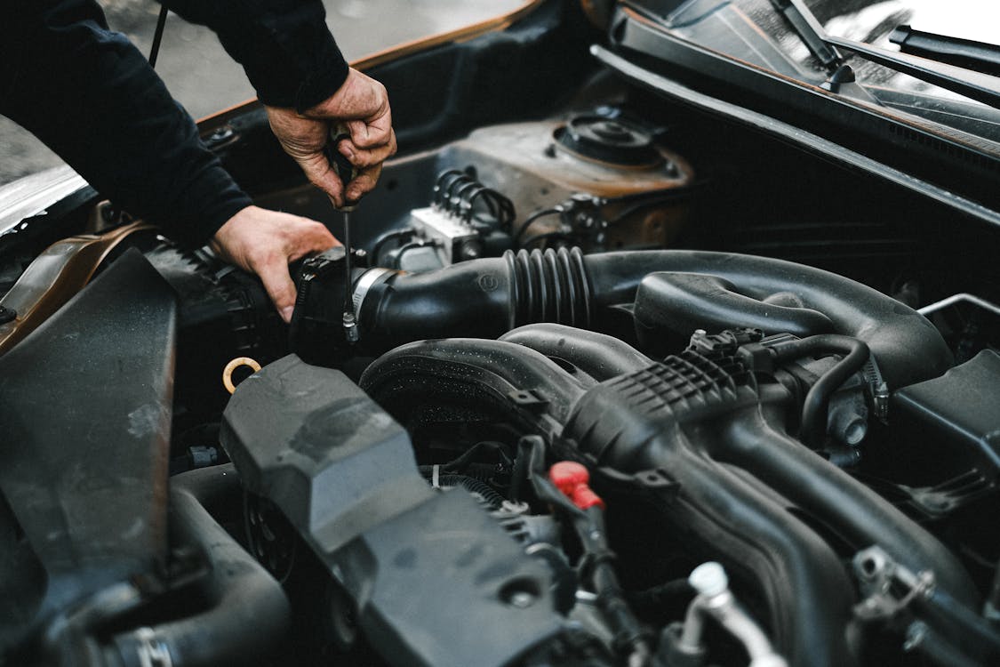 Mechanic checking car engine and battery connections during a car battery replacement inspection in Oklahoma City