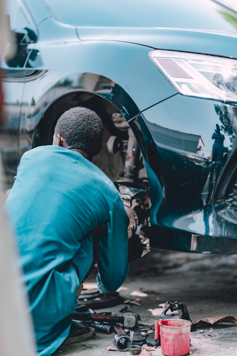 Mobile mechanic performing brake repair with wheel removed at customer's location