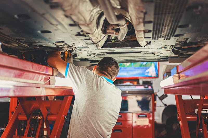 Professional mechanic working underneath a vehicle performing automotive repair